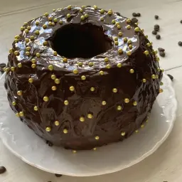 Szybka babka z majonezem i kakao, oblana błyszczącą czekoladą i ozdobiona złotymi kuleczkami.