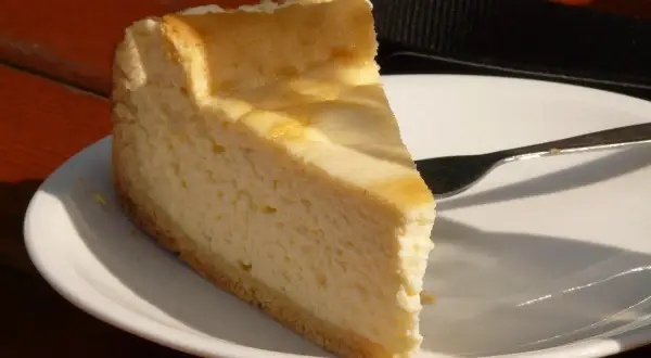 Pyszny sernik z 2 kg sera z wiaderka na talerzu, gotowy do zjedzenia. Idealny na deser.