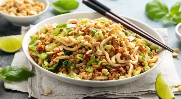 Pyszne danie z makaronem, mielonym mięsem i zielonymi warzywami, inspirowane przepisami na kapustę pak choi. Posypane orzeszkami ziemnymi.