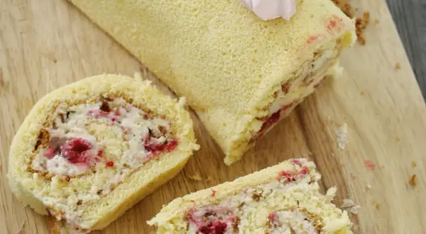 Puszysta rolada biszkoptowa z mascarpone i malinami, udekorowana różową bezą. Idealna na deser.