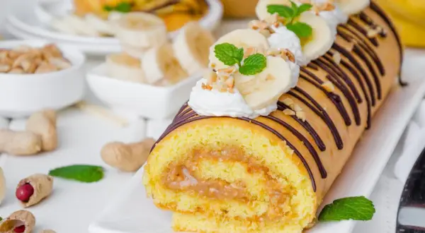 Najprostsza rolada biszkoptowa z kremem orzechowym i bananami, ozdobiona czekoladą i miętą.